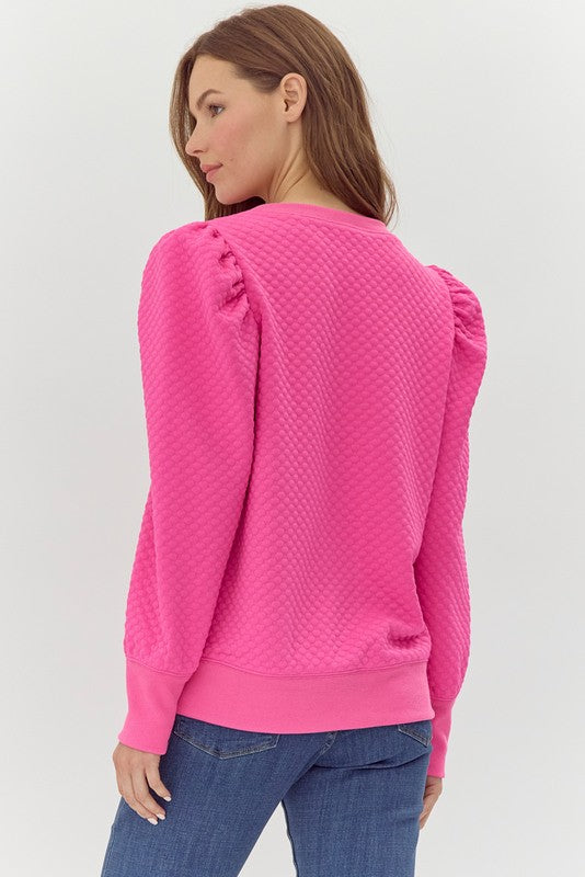 Woman wearing a pink textured sweater on a white background
