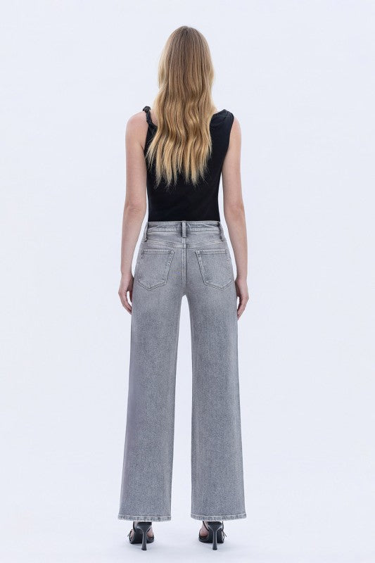 Person wearing gray wide-leg jeans and a black top on a white background