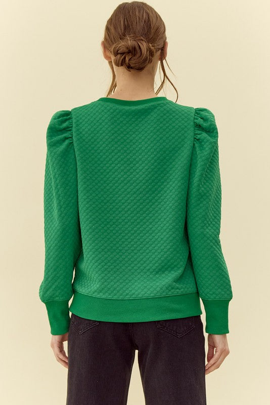 Green textured sweater worn by a person on a beige background