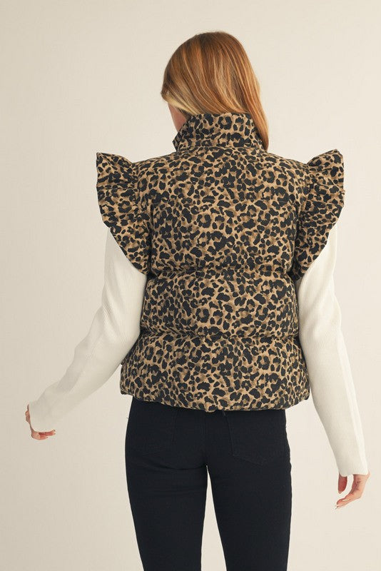 Person wearing a leopard print vest with ruffled sleeves on a plain background