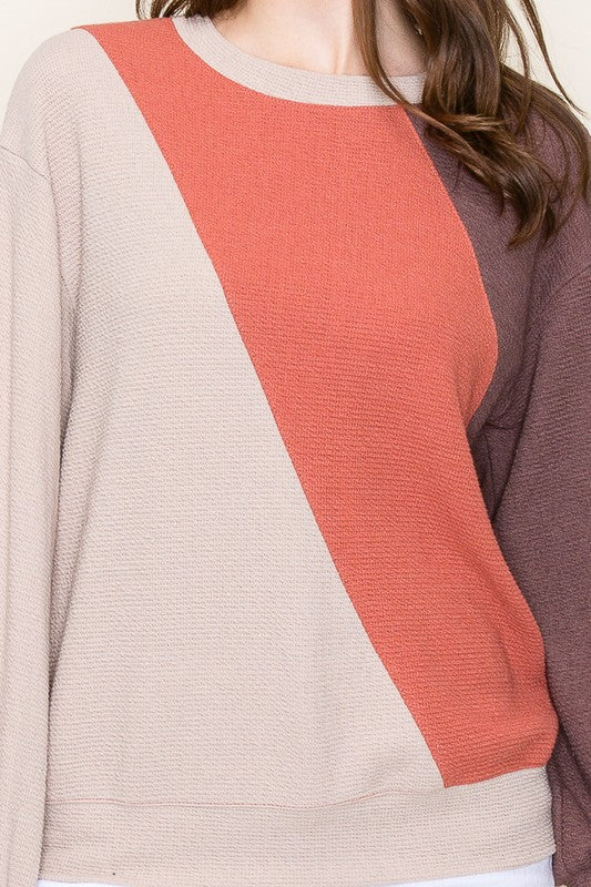 Color-blocked sweater with diagonal pattern on a neutral background