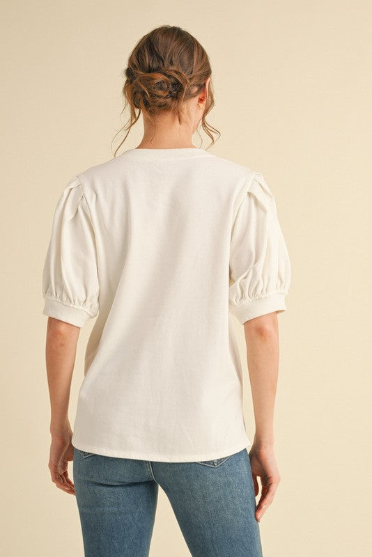 Person wearing a white blouse with short sleeves and blue jeans on a beige background