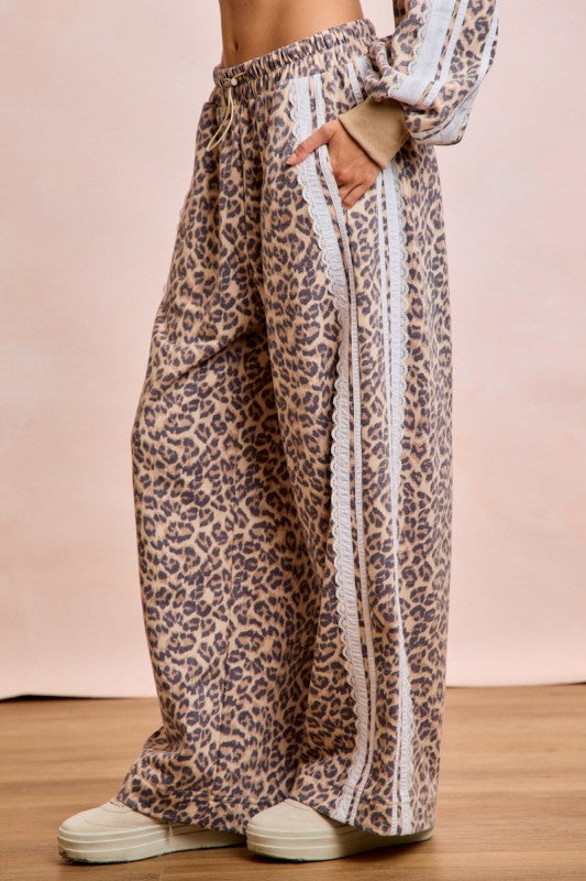 Women’s leopard print French terry wide leg sweatpants with lace side stripe detail and drawstring waistband.