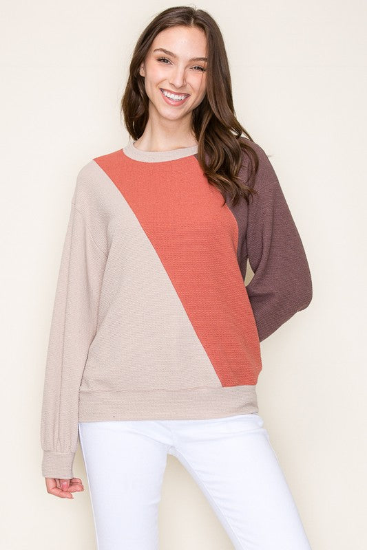 Woman wearing a color-blocked sweater with a plain background