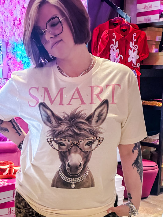 Women’s graphic tee featuring a stylish donkey wearing rhinestone leopard glasses, layered jewelry, and a SMART graphic with rhinestone accents.