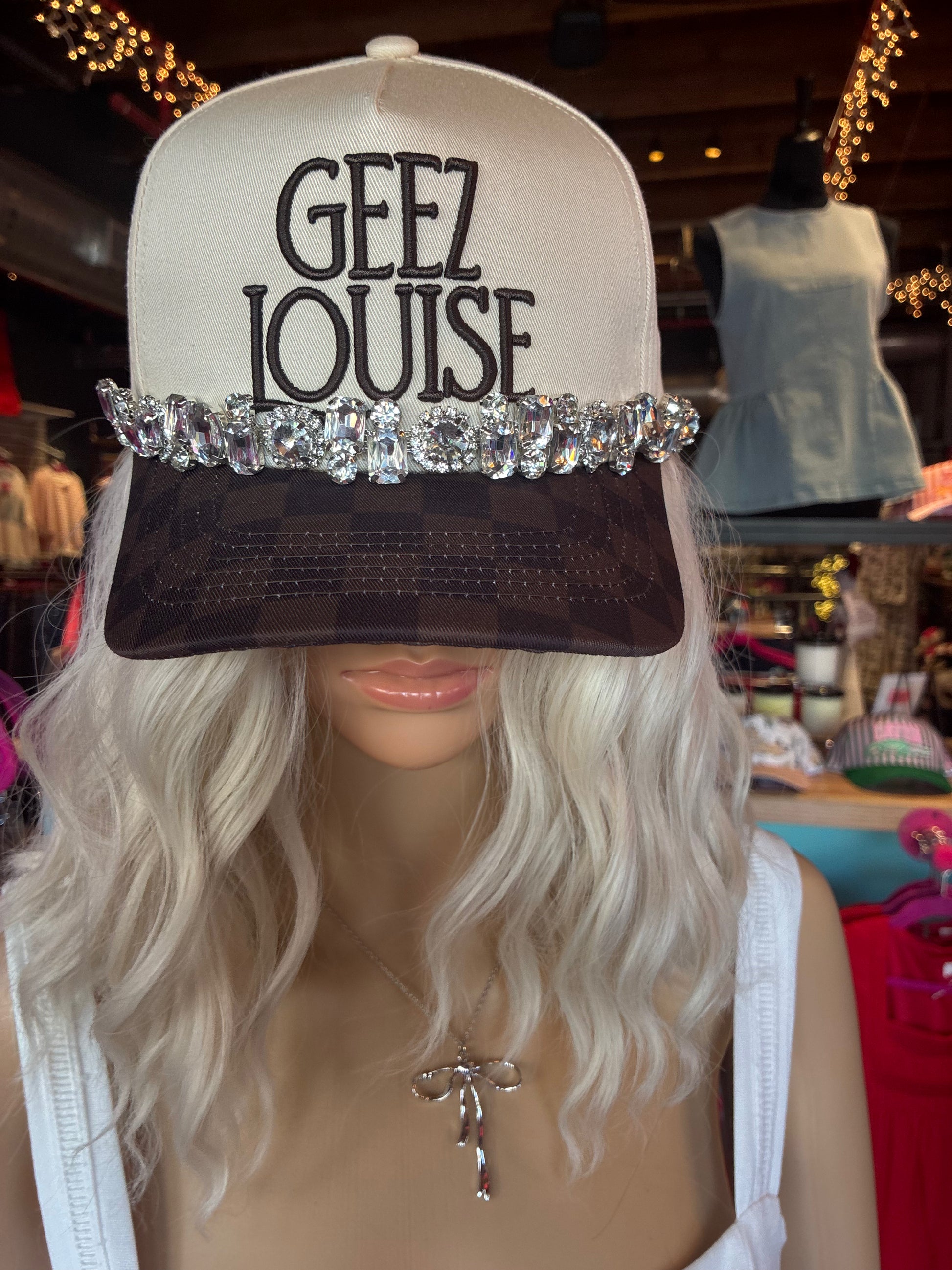 Cream and black trucker hat featuring Geez Louise embroidery and oversized crystal rhinestone embellishments on the brim.