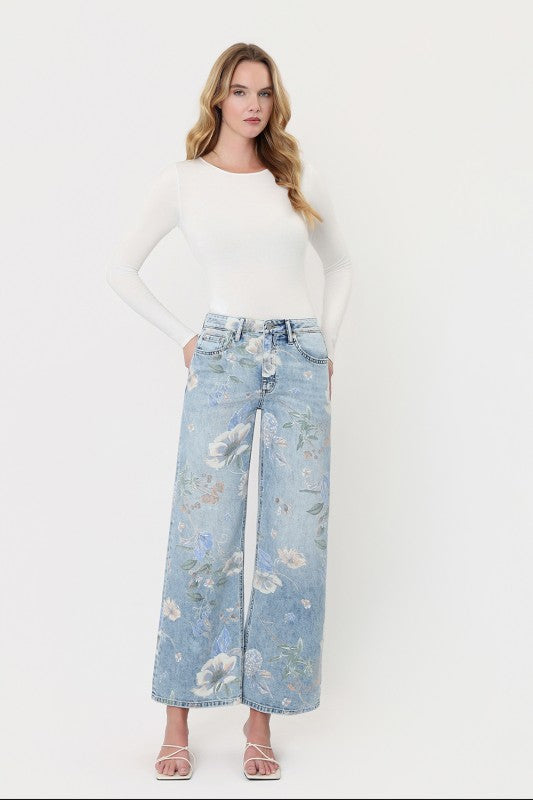 Model wearing Vervet by Flying Monkey light wash floral print super high-rise vintage flare jeans with an ankle-length wide-leg silhouette.