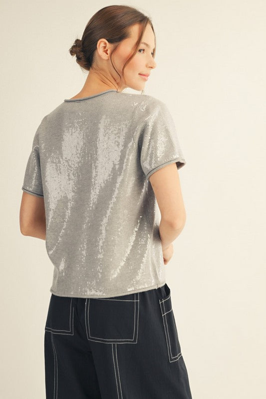 Gray sweater top covered in tiny sequins with raw edge detailing and relaxed boutique fit.
