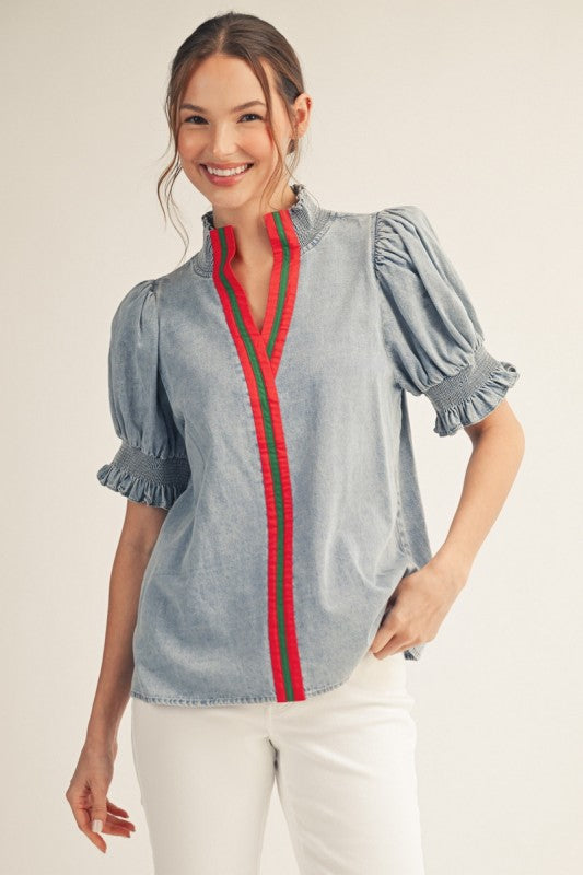 Washed denim puff sleeve top with smocked standing neckline and solid contrast detail.
