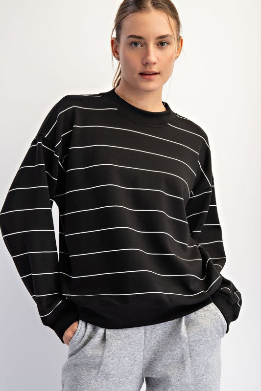 Person wearing a black and white striped sweater on a plain background