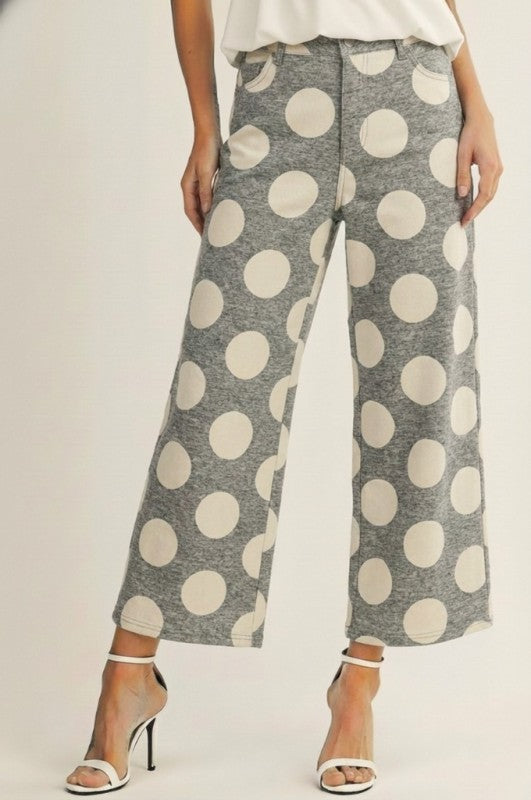 Woman wearing grey and ivory oversized polka dot wide leg cropped pants with white heels