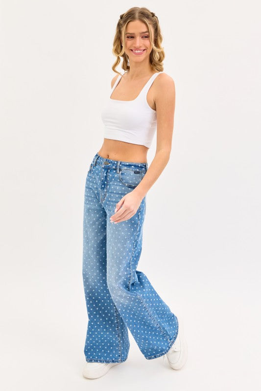 Woman wearing medium wash high rise wide leg jeans with white polka dot print and white crop tank top