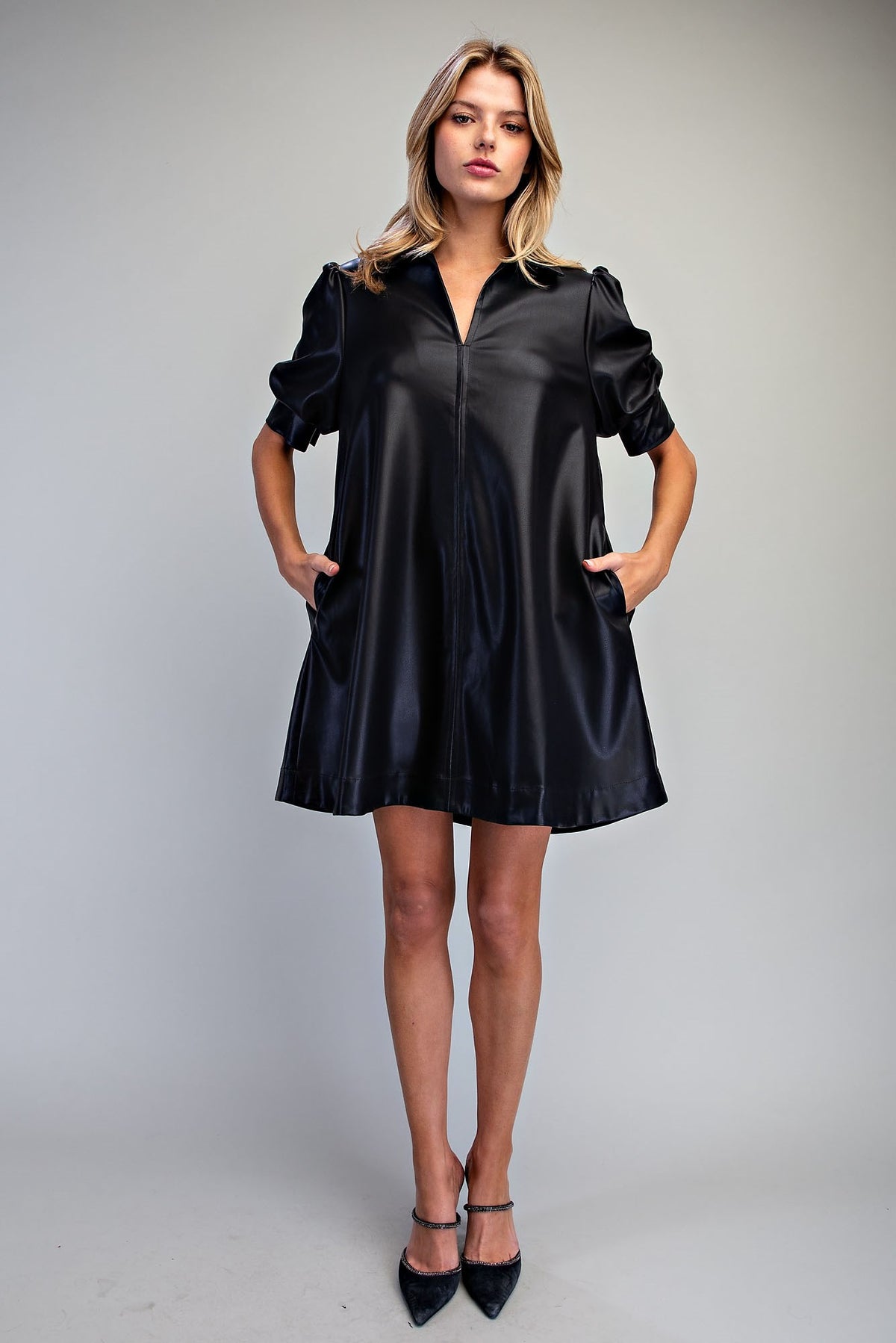 Woman wearing After Dark black faux leather puff sleeve mini dress with pockets