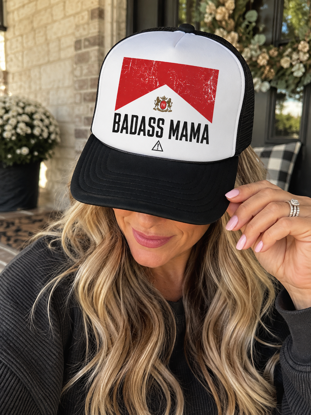 Black and white Badass Mama trucker hat with distressed red graphic, black bill and mesh back.