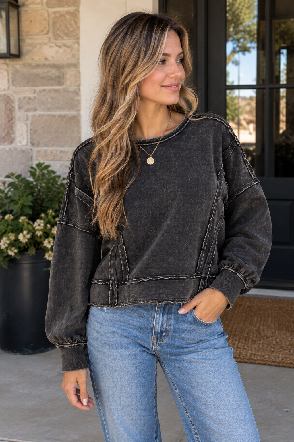 Woman wearing a black washed cotton sweatshirt with raw seam details, drop shoulders and a relaxed fit