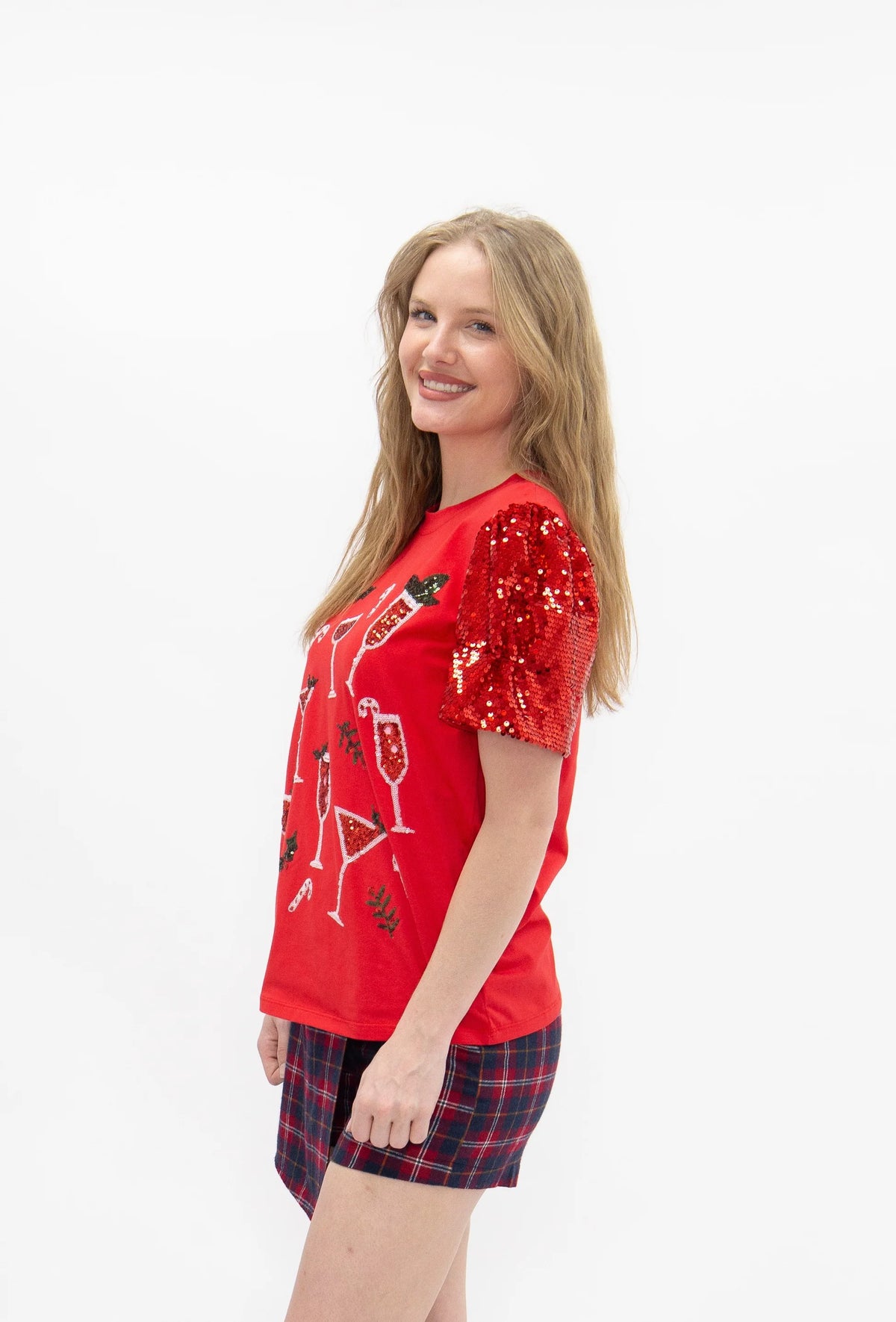 Side view of women's red Christmas graphic tee showing shimmering red sequin puff sleeve and holiday cocktail design.