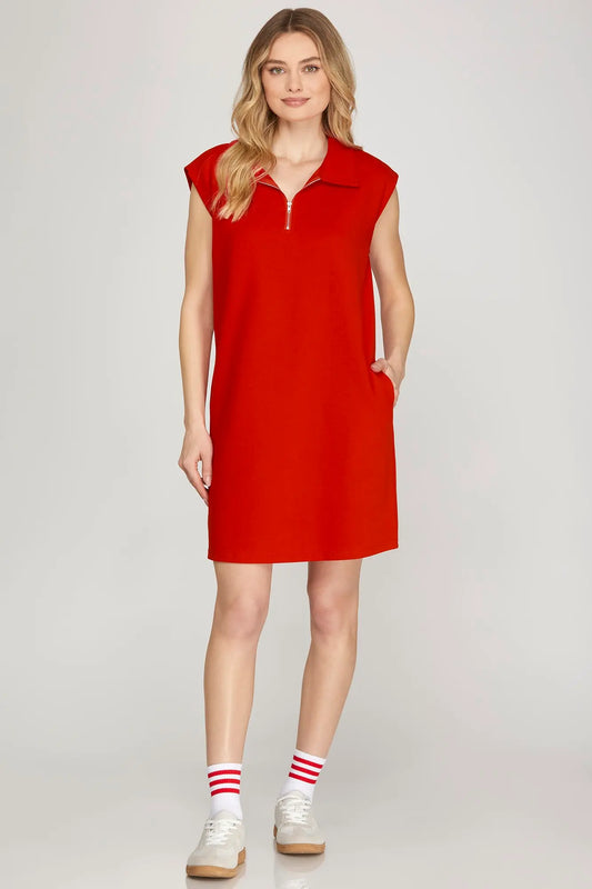 Woman wearing a red sleeveless dress on a plain background