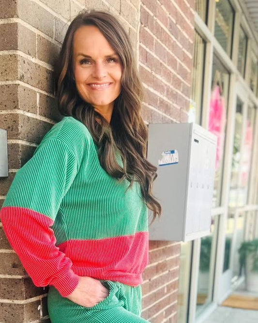 Woman modeling a green and red color block ribbed pullover with long sleeves and a relaxed fit outside a boutique.