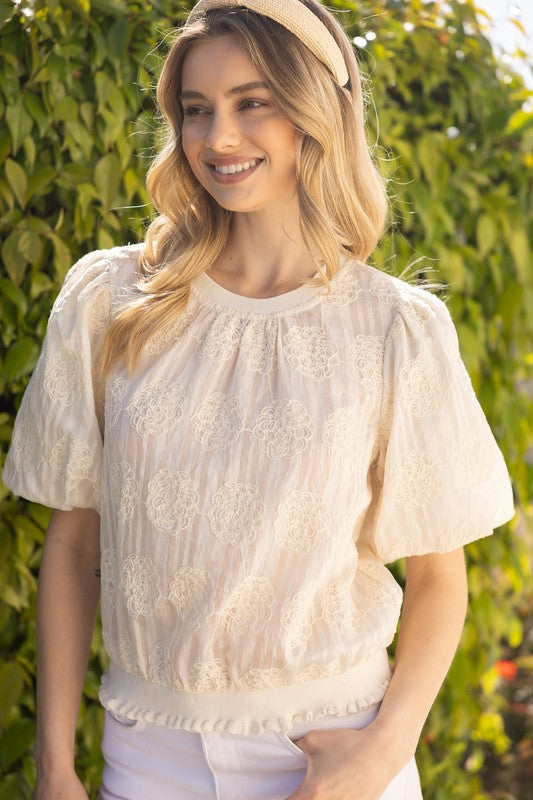 Woman wearing a white lace blouse with a blurred green background