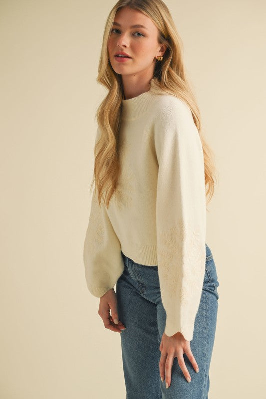 Ivory balloon sleeve sweater with embroidered floral details and mock neck