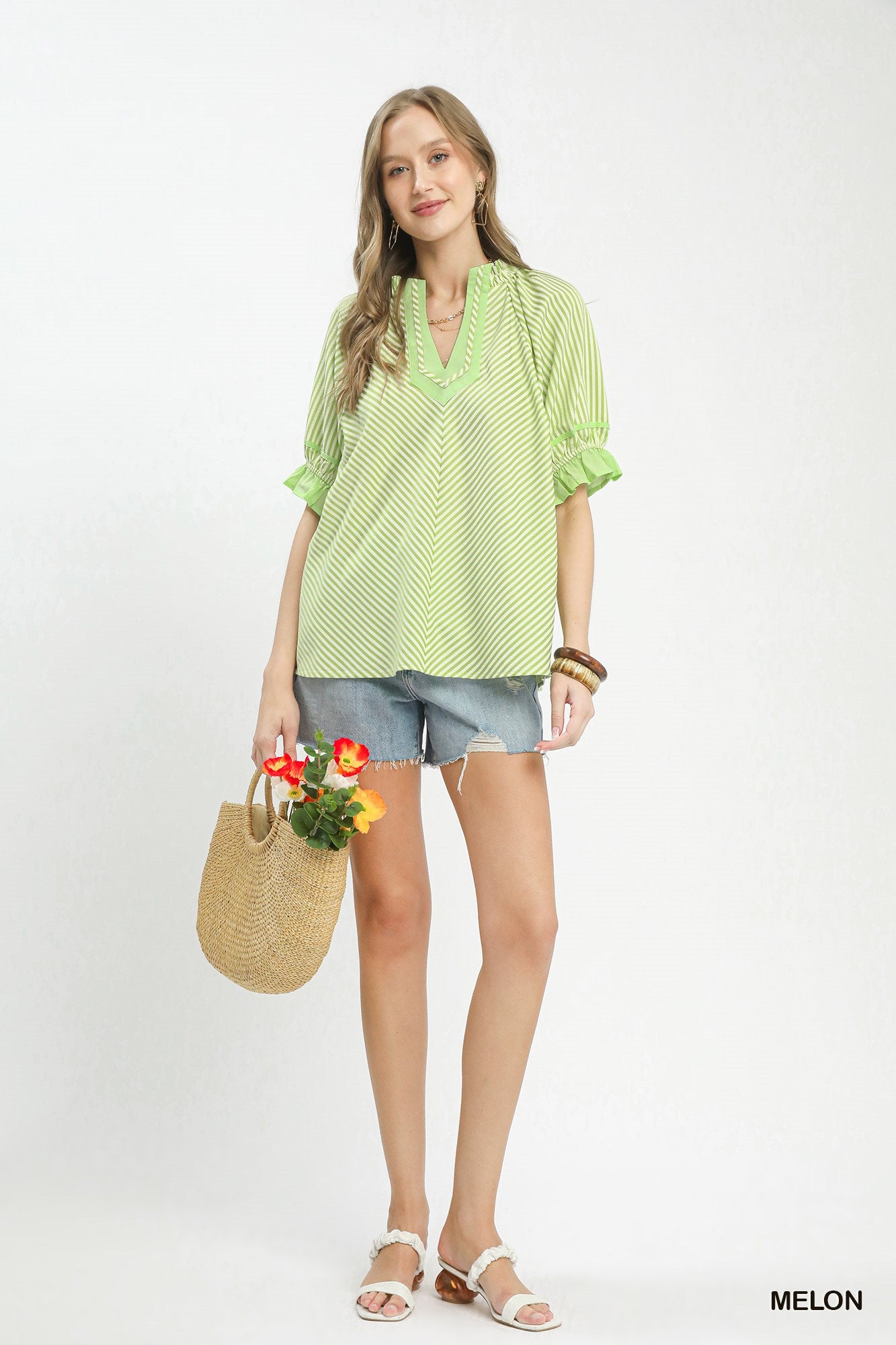 woman wearing melon green striped blouse with ruffle puff sleeves and split neckline with contrast trim