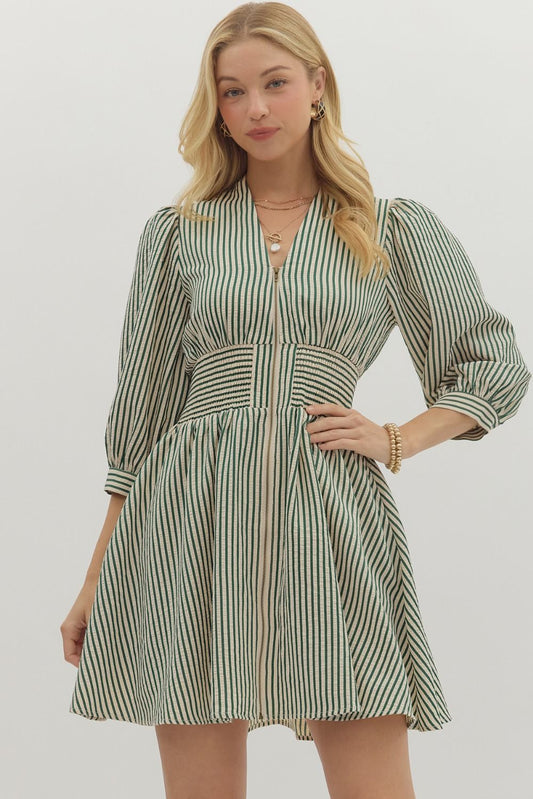 Woman wearing a green and white striped dress on a plain background