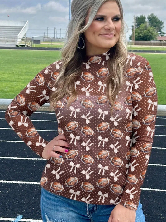 Women’s brown mesh game day top featuring footballs, bows, and polka dots styled with denim jeans from Twisted Sisters Shoetique.