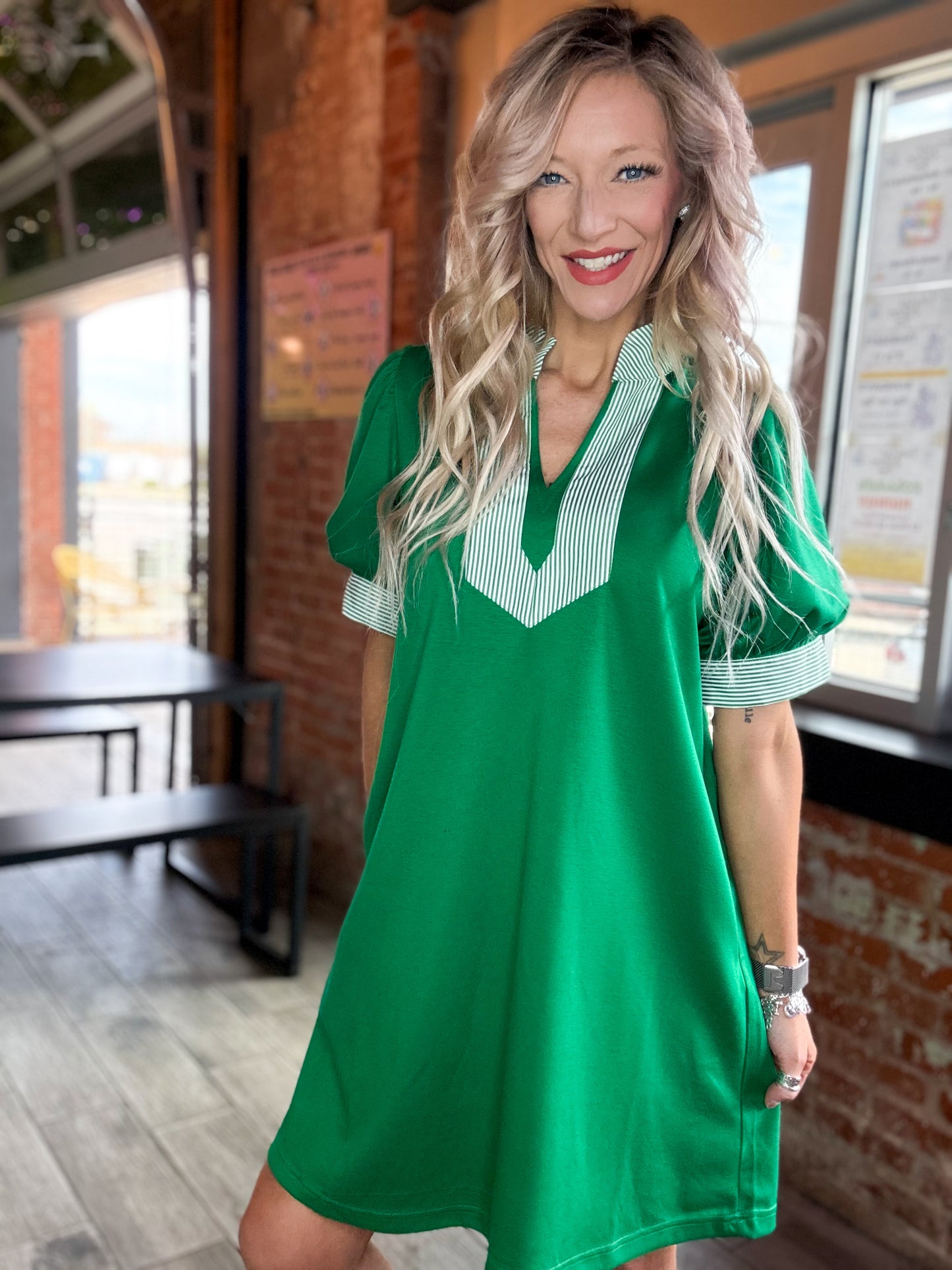 Woman wearing a green dress with white trim in an indoor setting