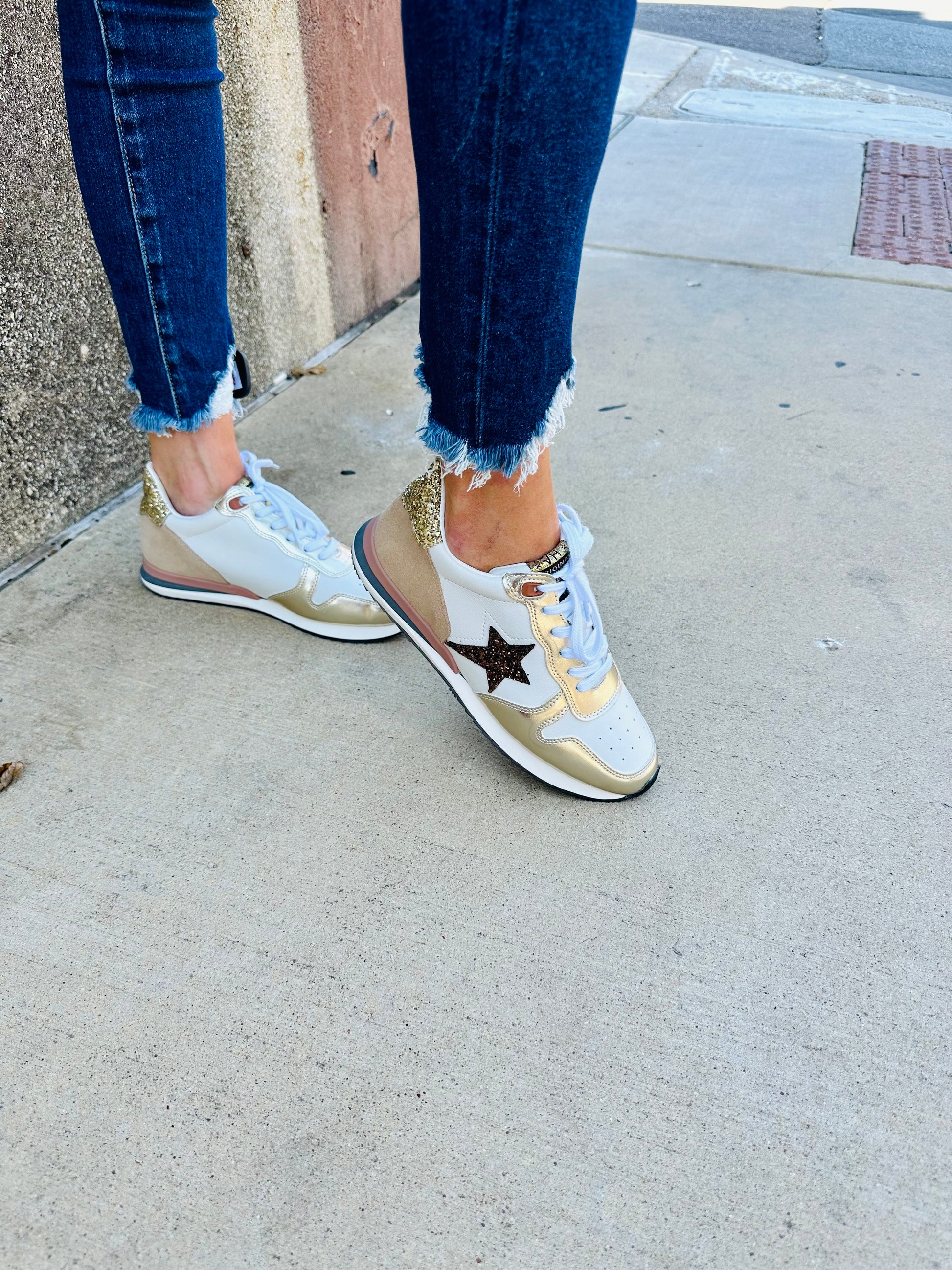 woman wearing Vintage Havana Rock 1 sneakers with white base, metallic gold and bronze accents, and star detail on side
