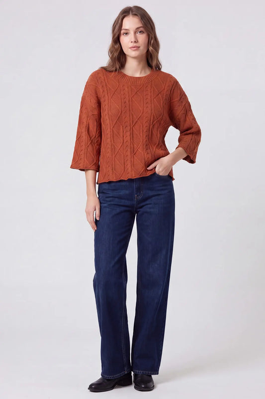 Women’s rust cable knit sweater with three-quarter sleeves styled with dark wash jeans